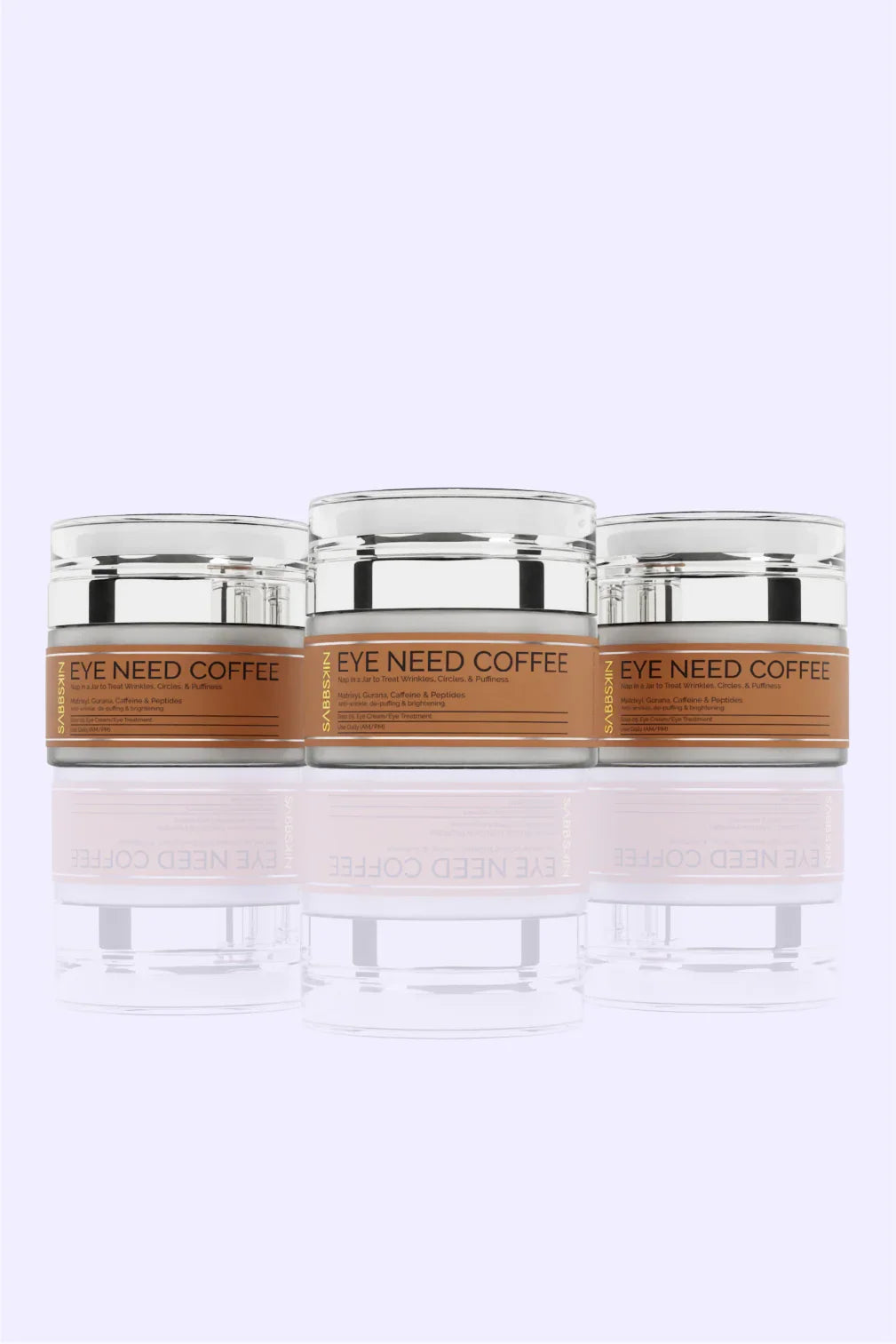 Three EYE NEED COFFEE eye cream jars with silver lids on a light purple background.